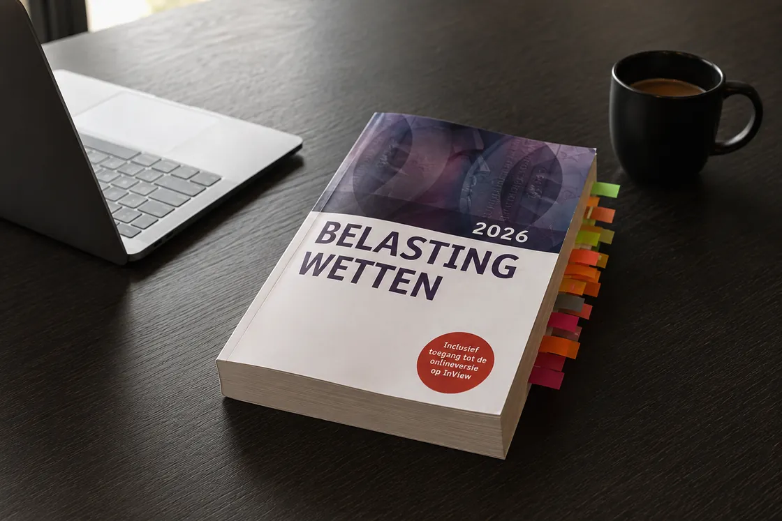 De wettenbundel Belastingwetten met tabbladen erin, op een bureau naast een laptop