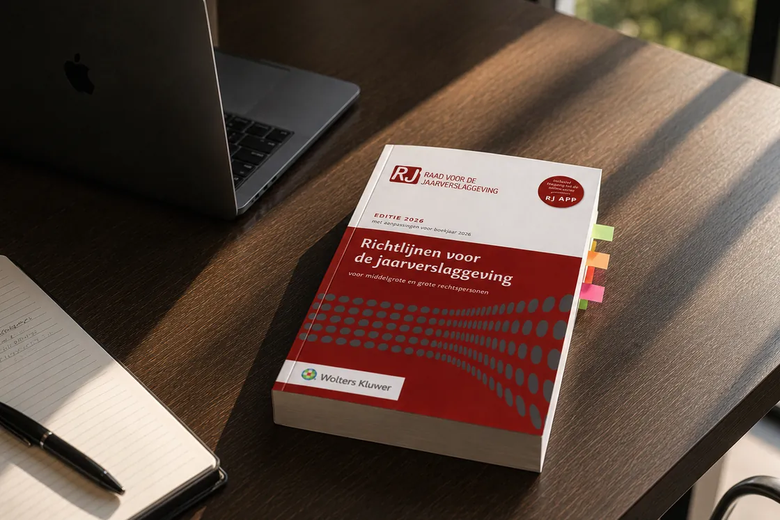 De Richtlijnen voor de jaarverslaggeving, editie 2026, met tabbladen erin, op een bureau naast een laptop en een notitieblok